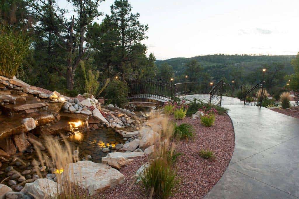 Scenic picture of stamped concrete sidewalk along a waterfall with bridge.